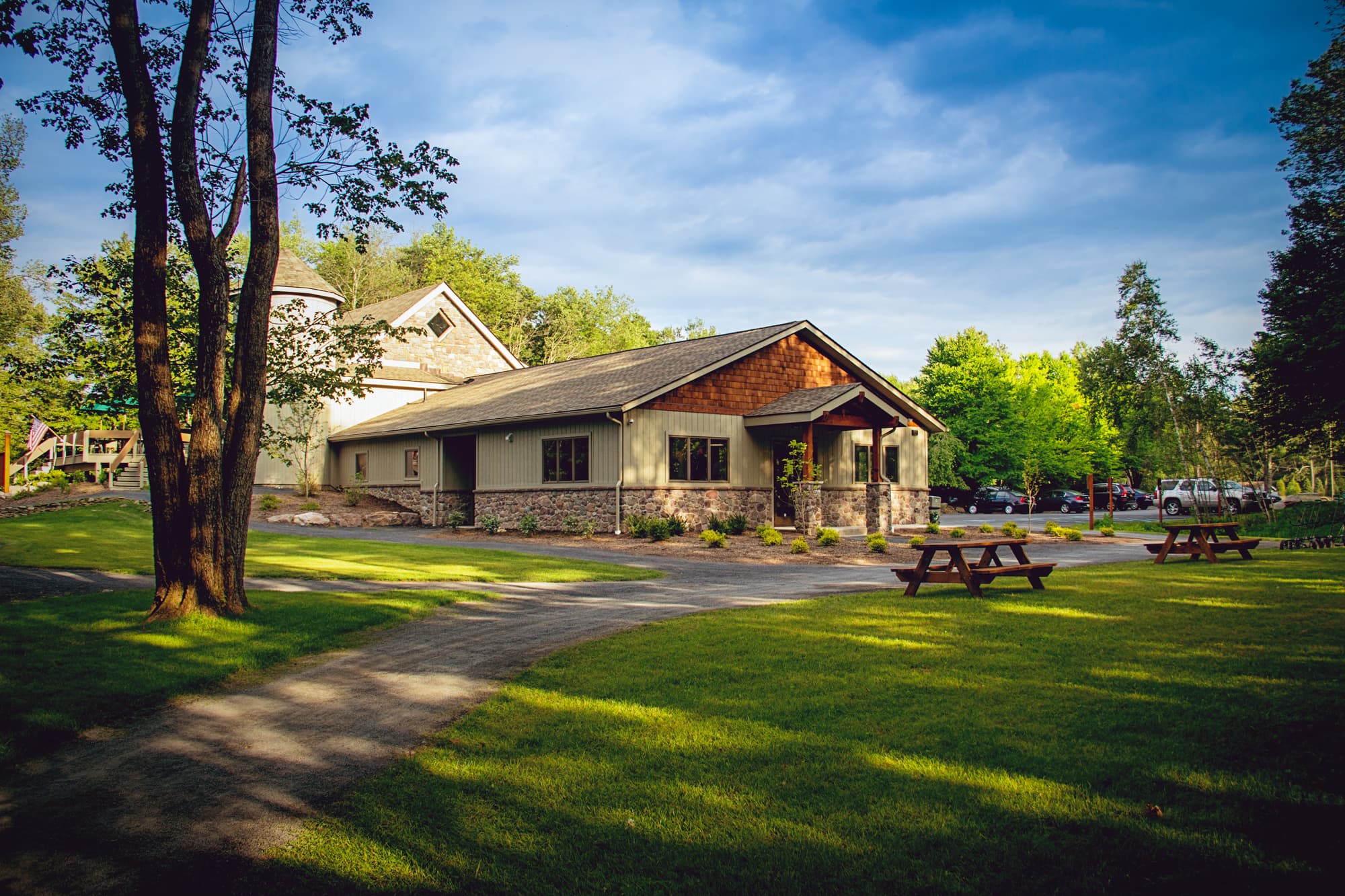 A landscaped area featuring a modern building and picnic tables under a blue sky.