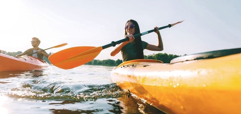 Two people kayaking on a sunlit body of water.