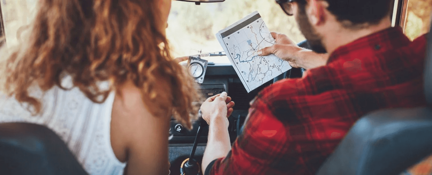 A couple examines a map while sitting inside a vehicle.