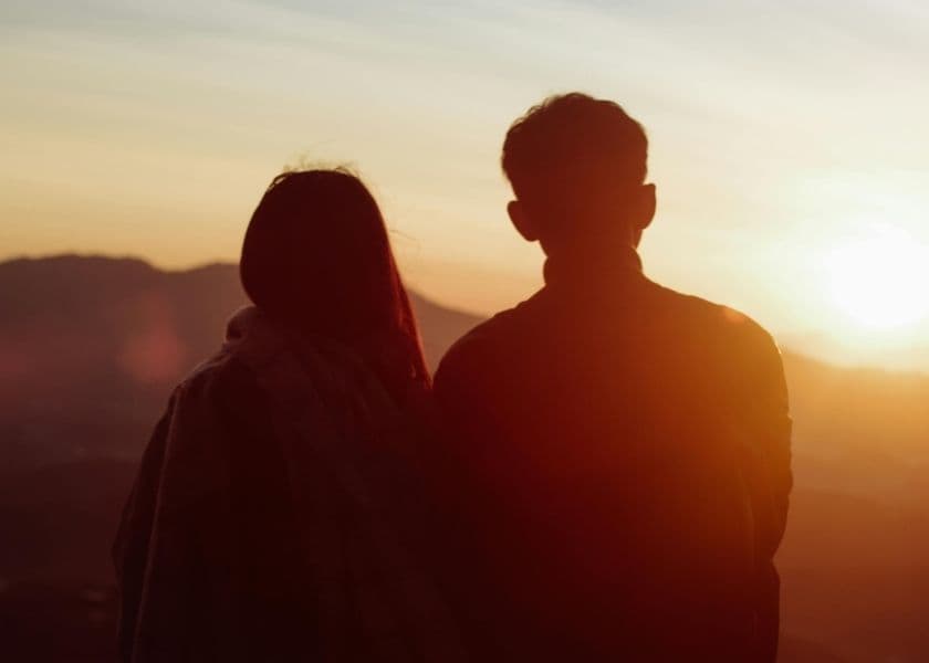 A couple watches the sunset from a mountain view. A couple watches the sunset from a mountain view.