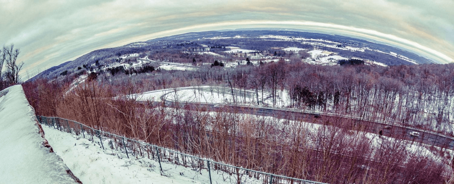 A panoramic view of a winter landscape with snow-covered trees and a winding road.