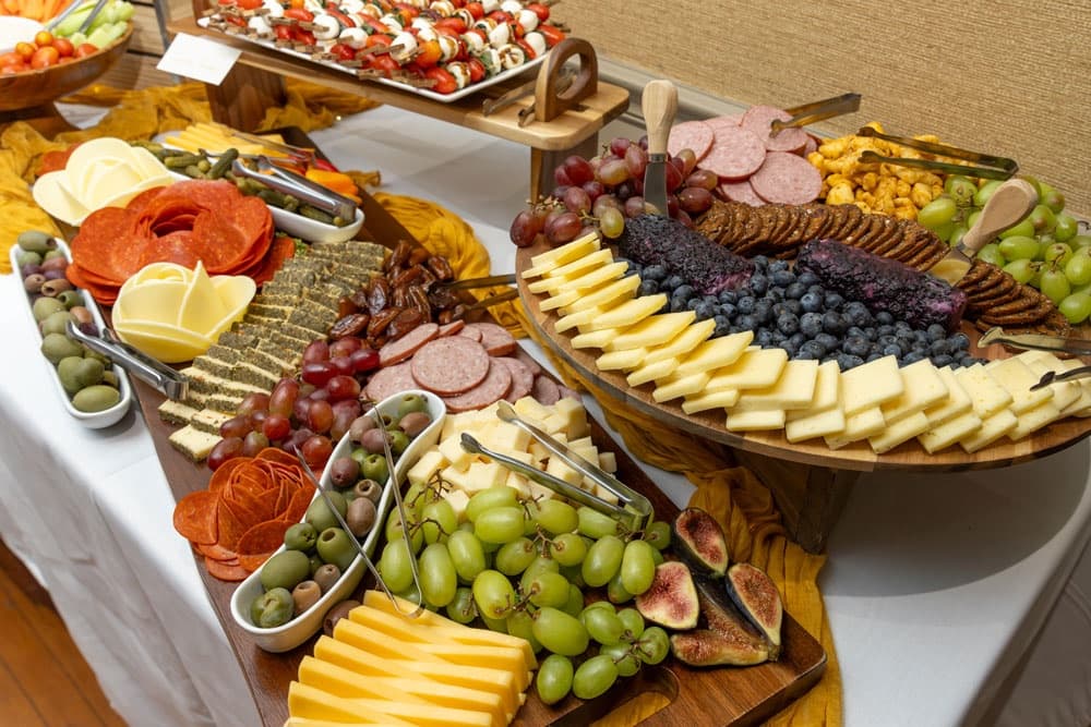 A beautifully arranged charcuterie and cheese platter featuring a variety of fruits, meats, cheeses, and snacks.