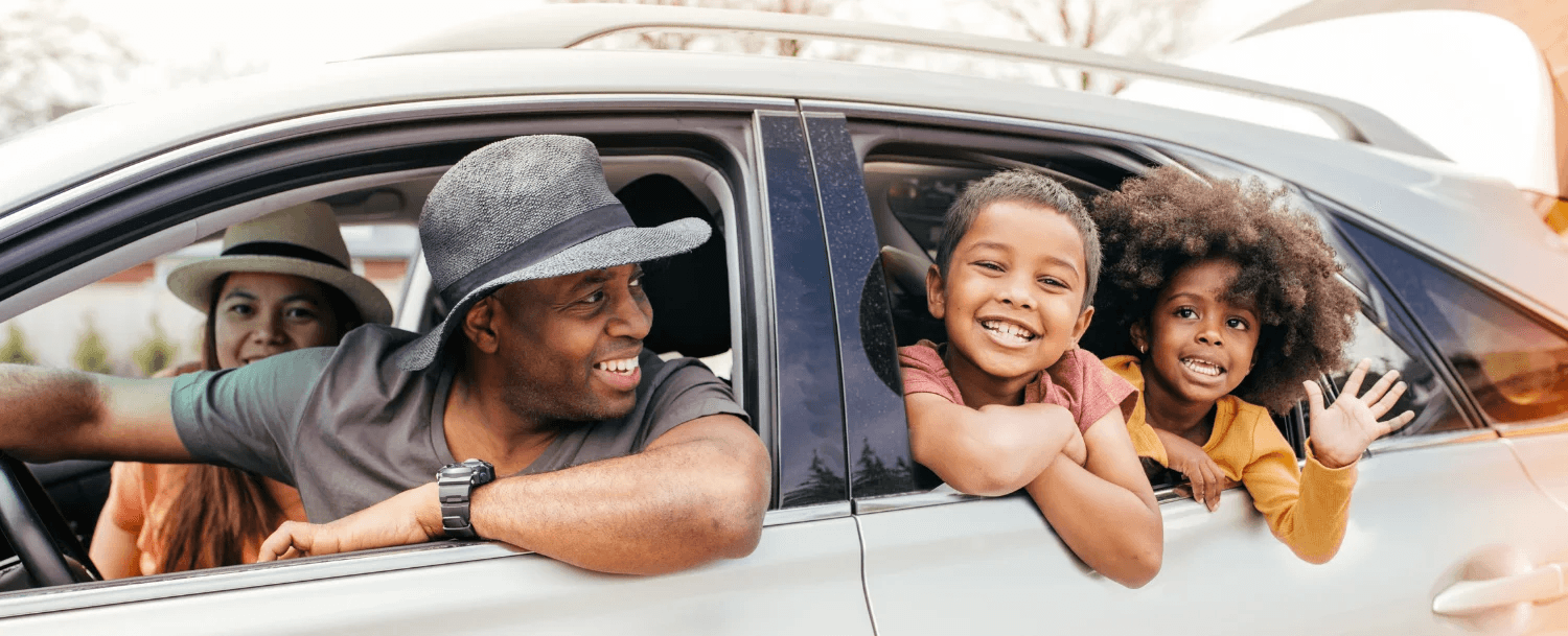 A happy family enjoys time together in a car, with parents and two children smiling and laughing. A happy family enjoys time together in a car, with parents and two children smiling and laughing.