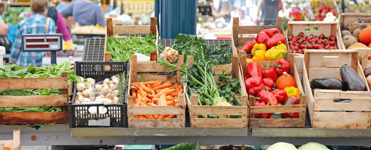 A vibrant display of fresh vegetables and fruits in wooden crates at a market. A vibrant display of fresh vegetables and fruits in wooden crates at a market.
