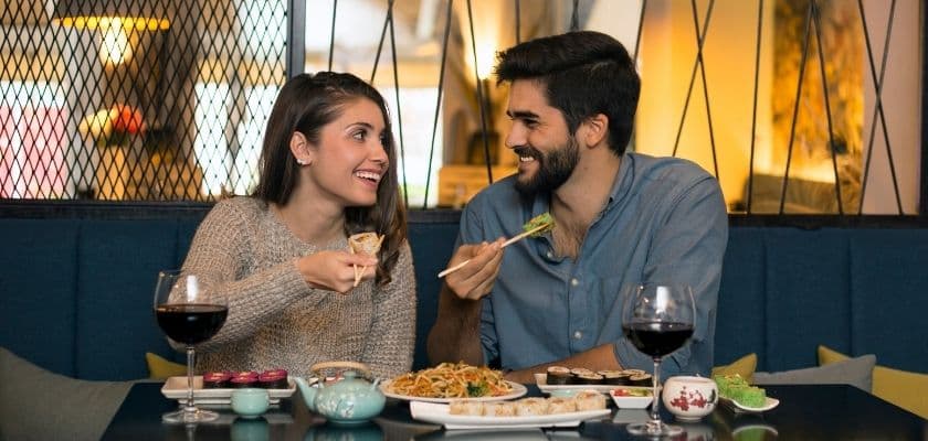 A couple shares a joyful meal at a restaurant, smiling and enjoying each other's company.