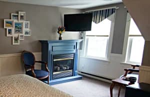 A cozy hotel room featuring a fireplace, television, and decorative wall photos.