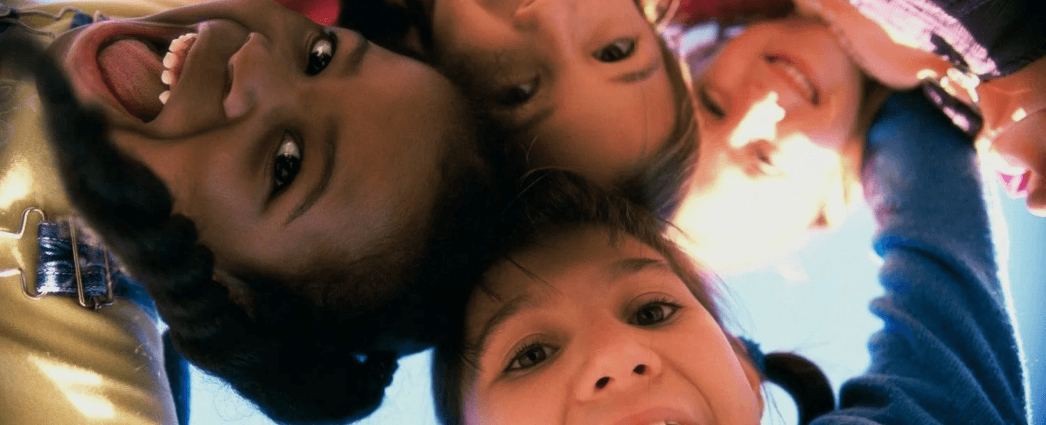 Four children smiling and posing together in a circle.