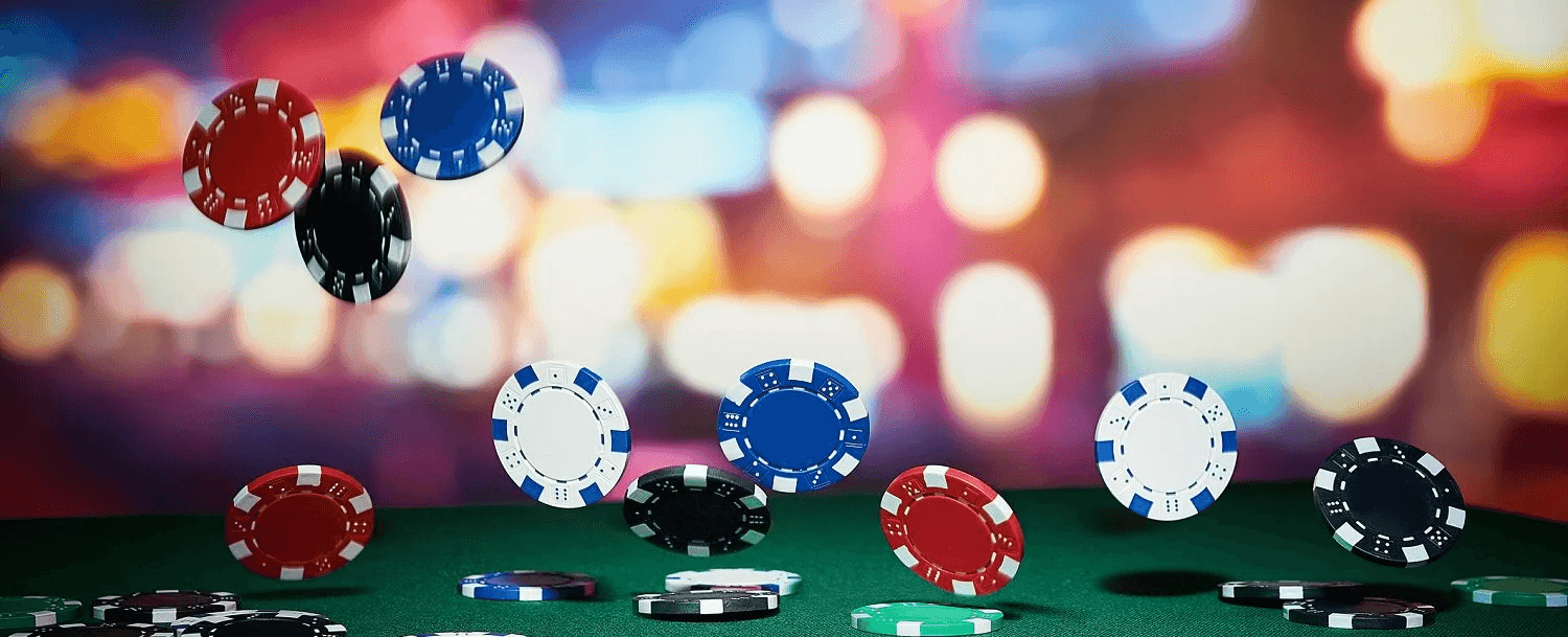 A variety of colorful poker chips are scattered mid-air against a blurred background.