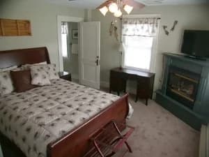 A guest room at a Bed and Breakfast Inn with a comfy bed, dresser, and fireplace